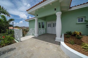 A building with a green facade, white columns, and a tiled roof. - Sea View Apt w/Pool & Near Jan Thiel Beach (Willemstad)