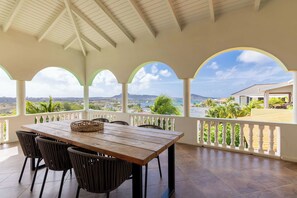 Un espace extérieur abrité, avec une table et des chaises, offrant une vue sur un paysage pittoresque.