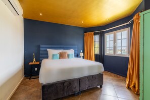 A room with a bed, a nightstand, a lamp, and a window with curtains. - Sea View Apt w/Pool & Near Jan Thiel Beach (Willemstad)
