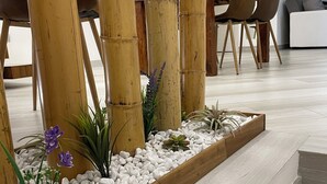 Un interior moderno con piso de madera, estructura de bambú y un comedor con sillas y una mesa.