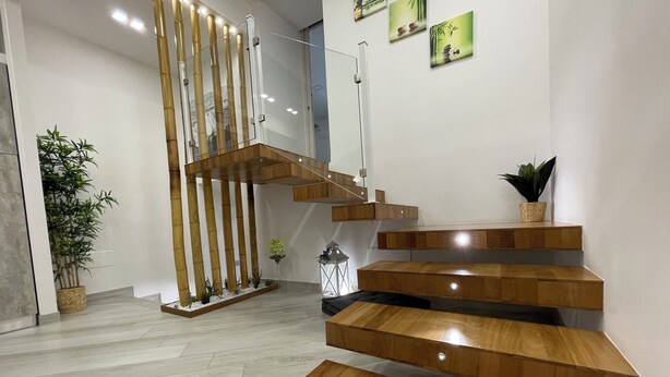 Una escalera moderna con escalones de madera y barandilla de vidrio.