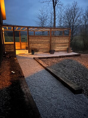A wooden structure with a glass enclosure, gravel flooring, and potted plants. - The squirrel relay (Dossenheim-sur-Zinsel)