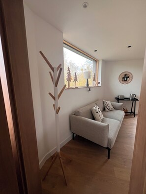 A modern living room with a sofa, a lamp, a coffee table, and a window with a view of trees. - The squirrel relay (Dossenheim-sur-Zinsel)