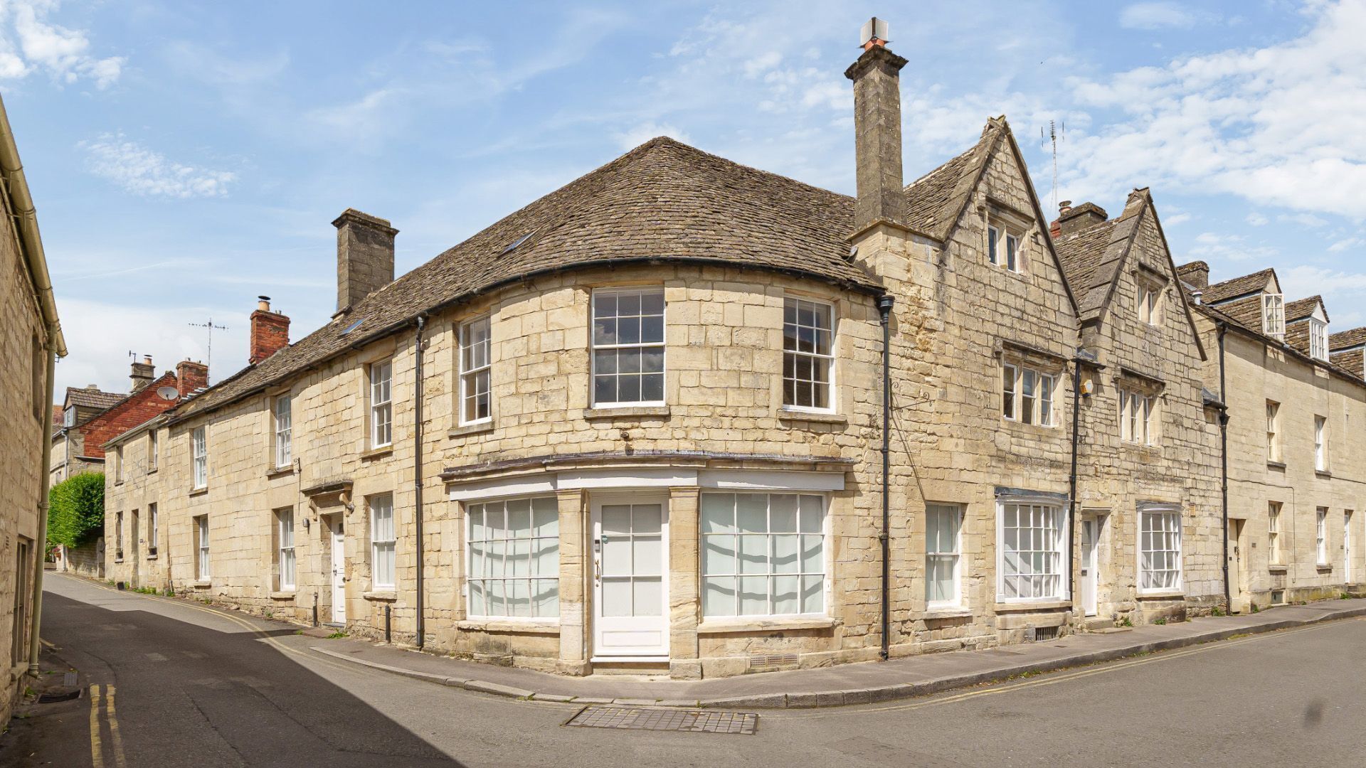 A stone building with a curved corner, multiple windows, and a visible door.