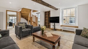Een moderne woonkamer met een trap, een flatscreen televisie en een stenen openhaard.