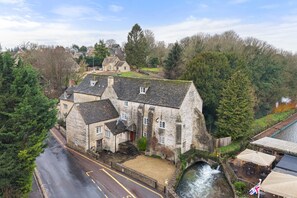 A stone building with a river in front, surrounded by trees. - Bibury Mill - Pet friendly, Bibury (Bibury)