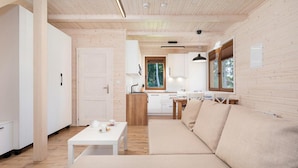 A modern interior with a wooden ceiling, a sofa, a dining table, and a kitchen area. - Comfortable Holiday Home , Summer Pool (Rewal)
