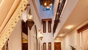 Um saguão de hotel com piso de azulejos, uma área de estar central e uma escadaria.