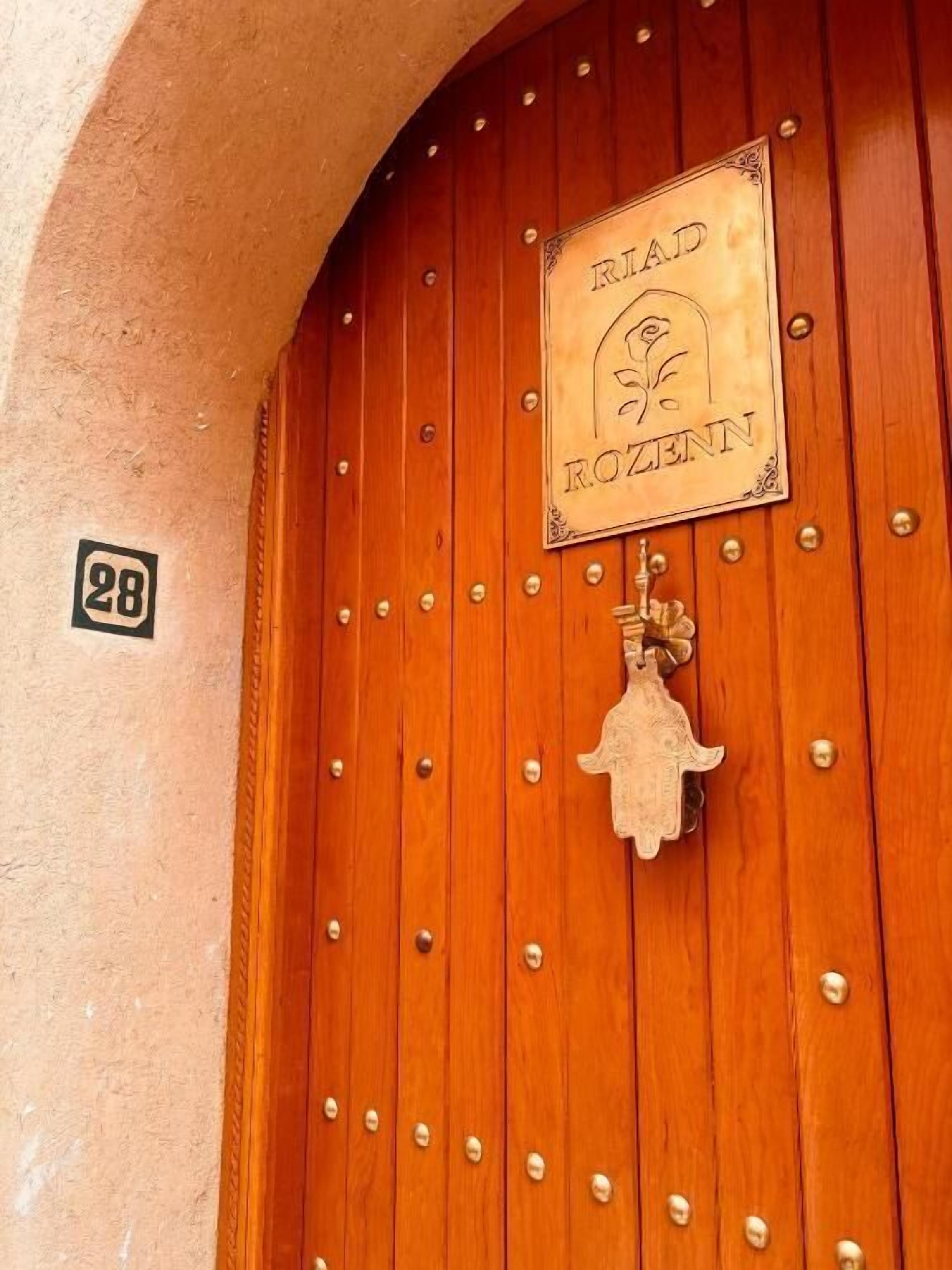 A wooden door with a sign reading 'Riad Rozenn' and a number '28' on the wall.