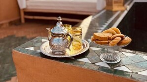 Uma cama com dossel, uma mesa com uma bandeja de comida e uma garrafa.
