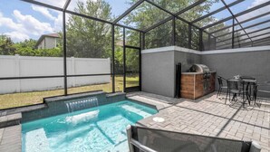 A backyard with a swimming pool, a barbecue area, and a covered seating area. - Premium Location Near Disney with Pool at Le Reve (Kissimmee)