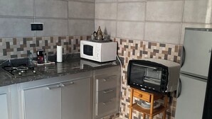 A kitchen with grey cabinets, a microwave, a toaster, and a kettle on the counter. - Woven Calm • 2BR Near Beach, Gateway to Chefchaouen (Martil)