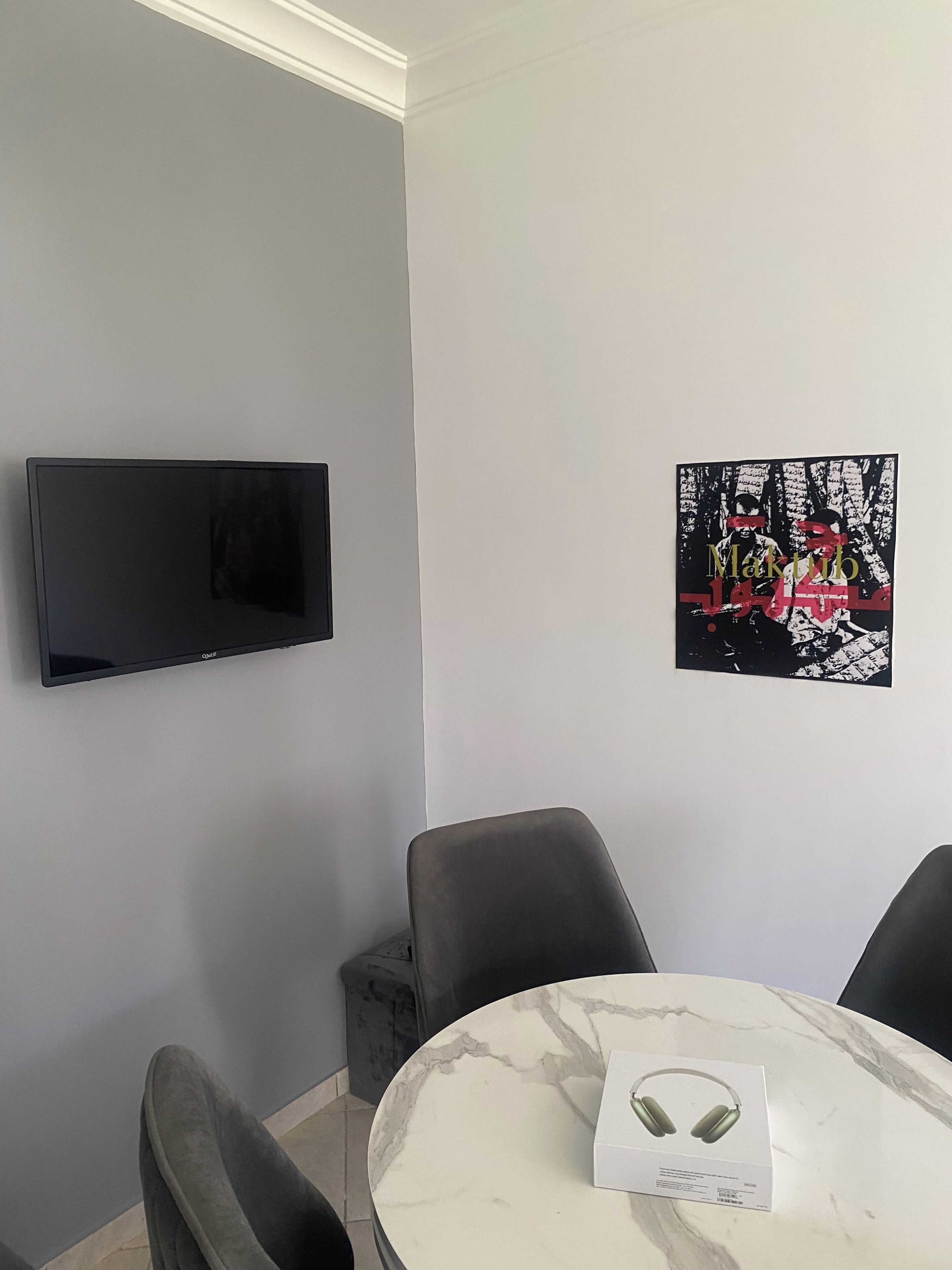 A modern room with a flat-screen TV, a marble table, and a framed artwork.