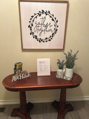 A wooden table with a framed welcome sign, a nameplate, and two potted plants. - Entire 4bedroom House - Secluded Ozark Escape (Reeds spring)
