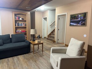 A living room with a sofa, armchair, bookshelf, lamp, and a painting on the wall. - Entire 4bedroom House - Secluded Ozark Escape (Reeds spring)