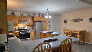 Une cuisine dotée de meubles en bois, d’un réfrigérateur, d’une cuisinière et d’un coin repas avec une table et des chaises.