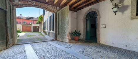 An outdoor covered area with a tiled floor, wooden beams, and a potted plant.