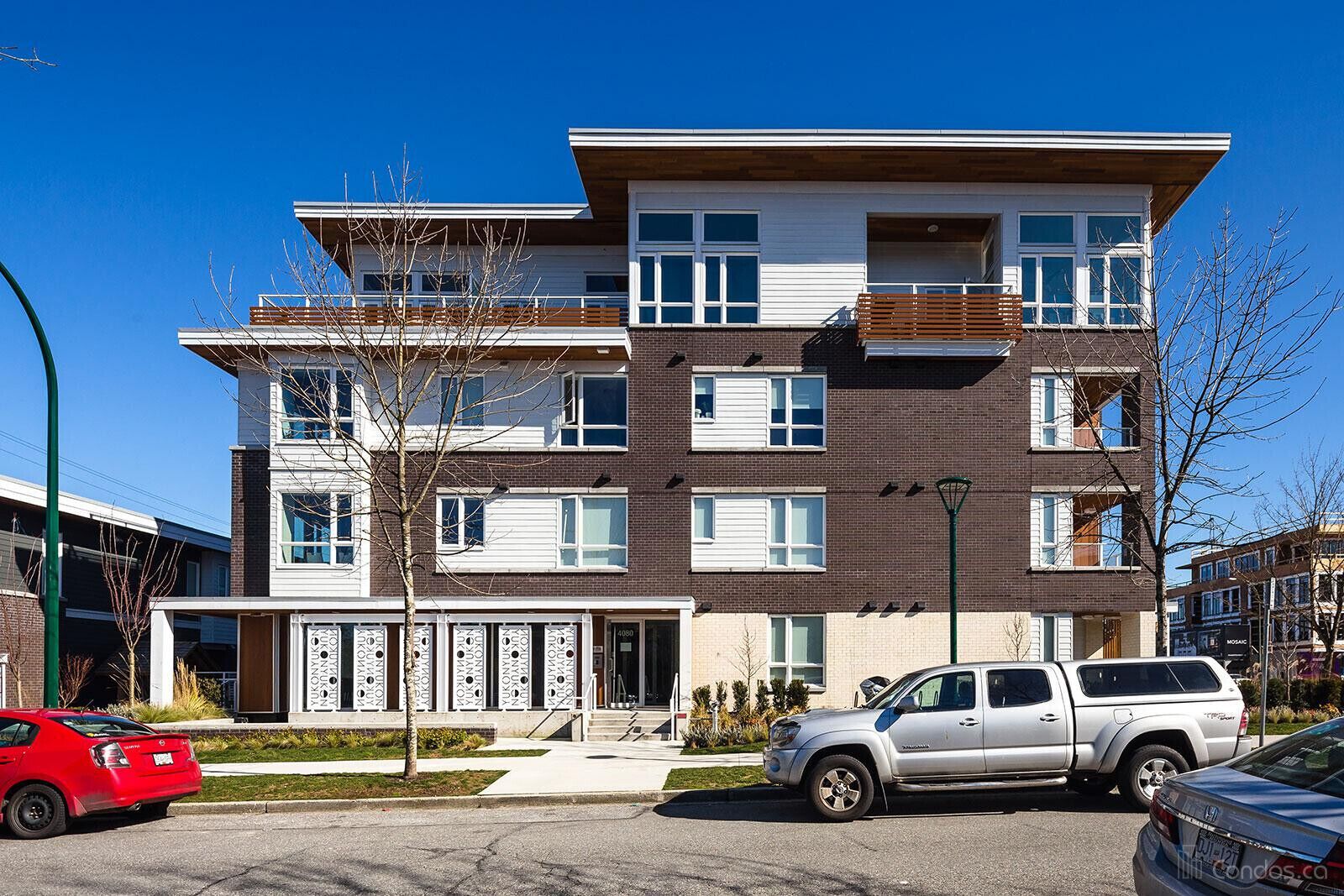 A multi-story residential building with a modern design, featuring balconies, large windows, and a visible entrance.