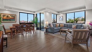 A spacious living area with a dining set, a sofa, and a view of the city. - Lux Ocean View Penthouse 2 Kings+, Steps to Beach (Lahaina)
