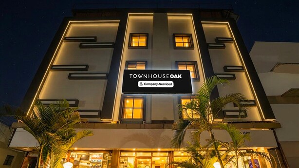 A modern building with a sign reading 'TOWNHOUSE OAK' and 'Company-Serviced.' - Premium Hotel Aditya Inn (Dharwad)