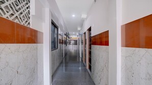 A corridor with marble walls, a patterned wall on the left, and a door at the end. - Premium Hotel Aditya Inn (Dharwad)