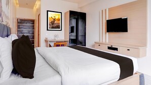 A hotel room with a large bed, a desk with a chair, a flat-screen TV mounted on the wall, and a framed picture above the desk. - Premium Hotel Aditya Inn (Dharwad)