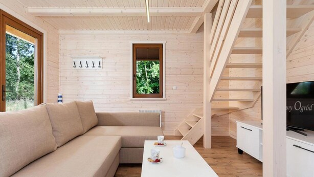A modern interior with a wooden floor, a beige sectional sofa, a white coffee table, and a television on a stand. - Comfortable Holiday Home , Summer Pool (Rewal)