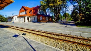A train station platform with a building featuring a red roof and white walls. - Comfortable Holiday Home , Summer Pool (Rewal)