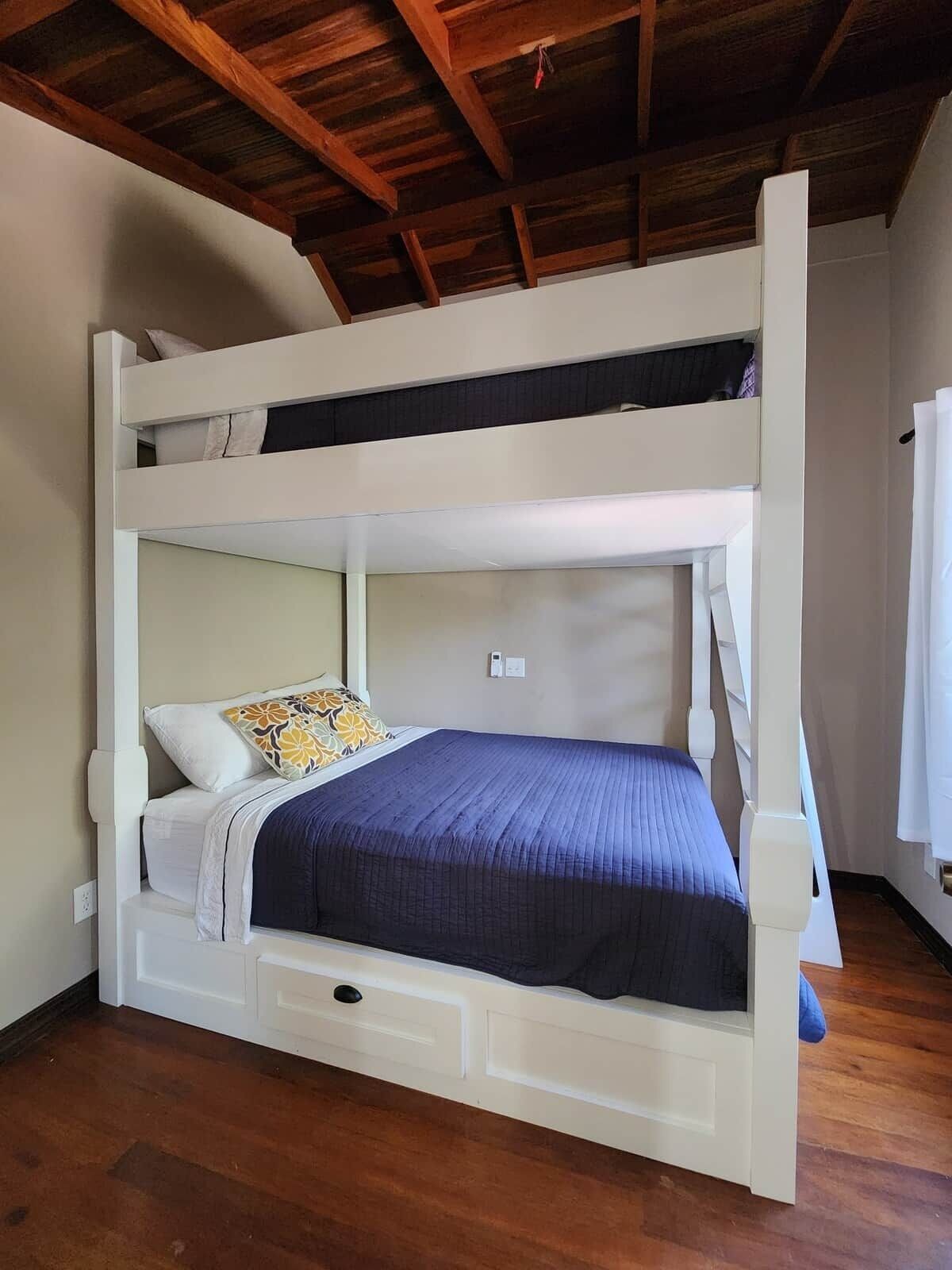 A bunk bed with a lower bunk, a drawer, and a white headboard.