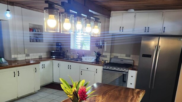 Una cocina con armarios de madera, un refrigerador de acero inoxidable y una isla de madera con un florero de flores.