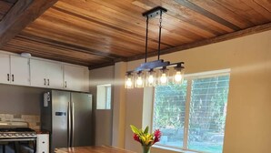 Una cocina moderna con una mesa de madera, bancos, un refrigerador y una ventana con persianas.