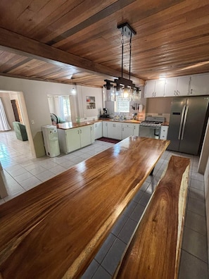 A modern kitchen with a large wooden island, stainless steel appliances, and a hanging light fixture.