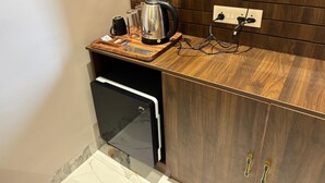 A compact kitchenette with a built-in oven, a kettle, and a coffee maker on a wooden countertop.