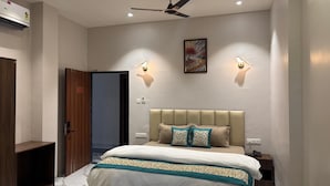 A bedroom with a bed, bedside lamps, a ceiling fan, and a painting on the wall.