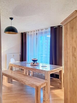 Ein Essbereich mit einem Holztisch, Stühlen, einer Schüssel und einer hängenden Leuchte.