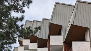 Ein mehrstöckiges Gebäude mit zeitgenössischer Architektur, Balkonen und einer Holzfassade.