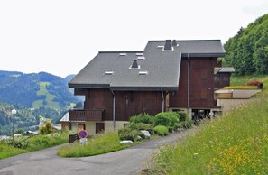 A modern two-story building with a sloped roof, situated on a hillside with a view of a valley. - Ground floor, balcony, 26m², Les Gets (Les Gets)