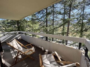A balcony with two wooden lounge chairs, a concrete floor, and a view of a forested area. - 300m from shops, 3rd floor, balcony, ski locker, 60m², Vars (Vars)