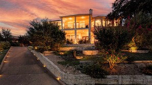 A modern two-story house with a well-lit entrance and a landscaped garden.