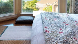 A bedroom with a large window, a ceiling fan, and a bed with a floral bedspread.
