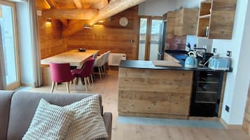 En inredning med träpanel, en soffa, ett matbord, stolar och ett köksområde.