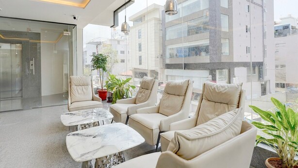 A modern lounge area with leather chairs, a marble table, and potted plants. - Townhouse Oak Aecs Layout Brookfield (Bengaluru)