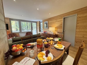 A dining area with a wooden table set for a meal, surrounded by wooden walls and large windows. - 300m from shops, 5th floor, terrace, ski locker, 74m², Vars (Vars)