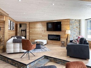 A modern living room with a fireplace, wooden walls, and a television. - 100m from ski slopes, 3rd floor, view ski slopes, terrace, fireplace or stove, tv, ski locker, 125m² (Les Orres)