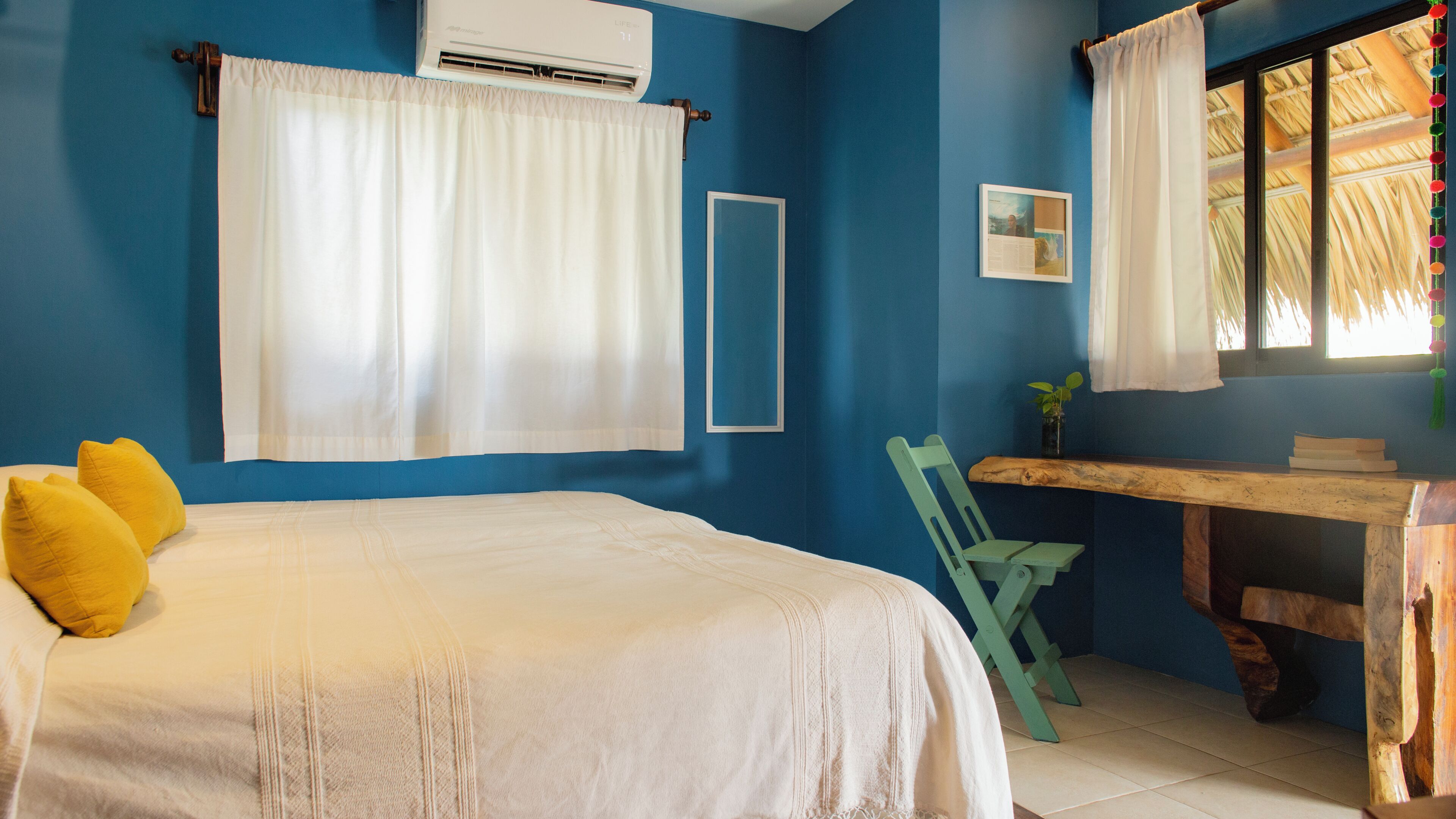 Une chambre à coucher avec un lit, un bureau, une chaise et une fenêtre avec des rideaux.