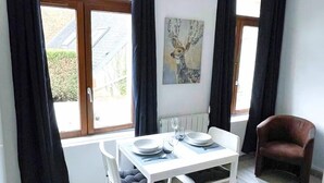 A dining area with a table set for two, a chair, and a radiator.