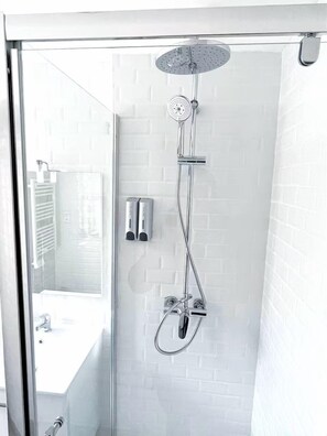 Een moderne douchecabine met een glazen deur, een handdouche en een wandmengkraan.