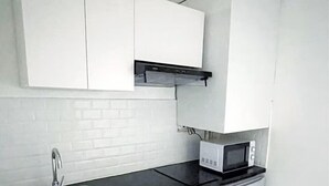 A compact kitchen with a sink, countertop, microwave, and a small refrigerator.