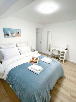 Quarto de hotel com cama, escrivaninha e espelho.