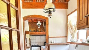 A kitchen with wooden cabinets, a tiled floor, and a hanging light fixture.